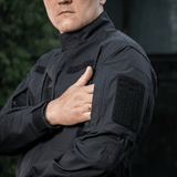 M-Tac Jakke Patrol Flex med velcrolommer og taktisk design, egnet til praktisk brug og komfort, fremvist udendørs.