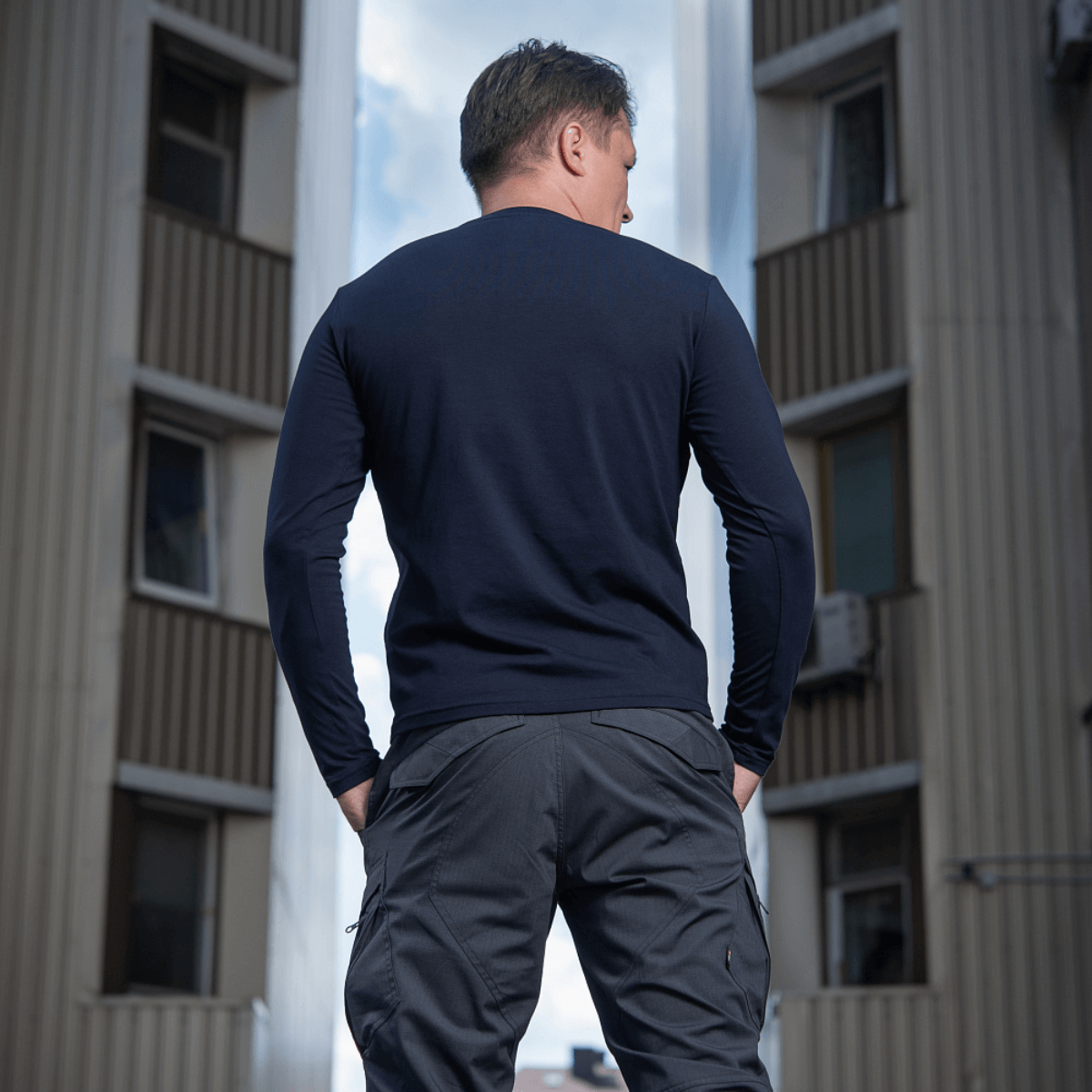 Mand iført M-Tac Long-sleeve T-shirt 93/7 i en byindstilling, viser slidstærk pasform og stilfuldt design