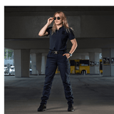 Kvinde iført M-Tac Bukser Aggressor Dame Flex i bymiljø, viser lette, tætsiddende bukser med Teflon-impregnering mod vand og snavs.