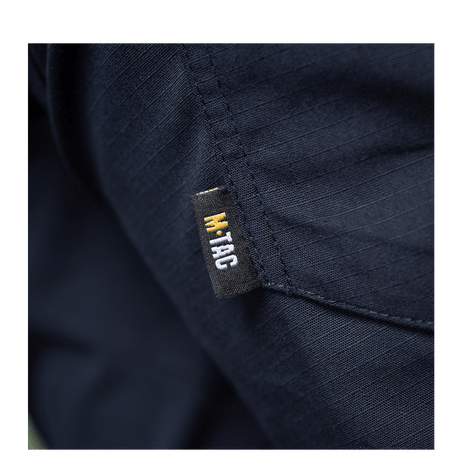 Detaljebillede af M-Tac Bukser Aggressor Dame Flex med M-Tac logo på mørkeblå materiale.