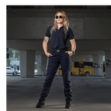 Kvinde iført M-Tac Bukser Aggressor Dame Flex under en bro, klar til træning eller arbejde. Innovative, lette bukser med Teflon.