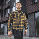 M-Tac Redneck Skjorte i navy blue/gul plaid, stilfuld og holdbar taktisk skjorte til arbejde og fritid, set på en person foran bygninger.
