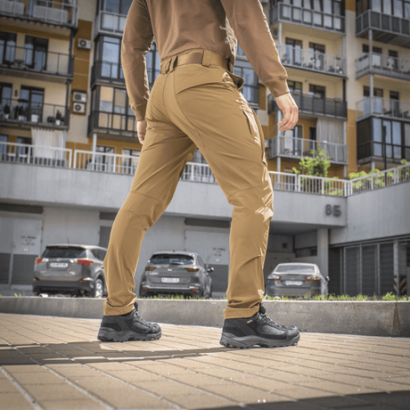 Mand bærer M-Tac Bukser Rubicon Flex på gaden, viser bevægelsesfrihed med 4-Way Stretch stof og innovativ cargo-lomme design
