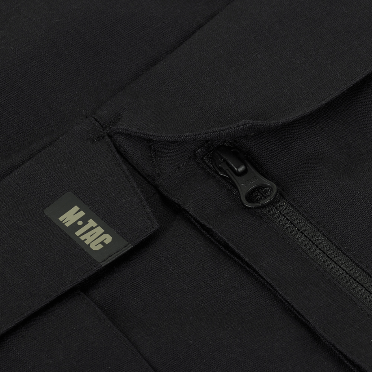 Close-up af M-Tac Bukser STURM NyCo Extreme Gen.II lynlås med M-Tac logo, fremhæver holdbarhed og design.