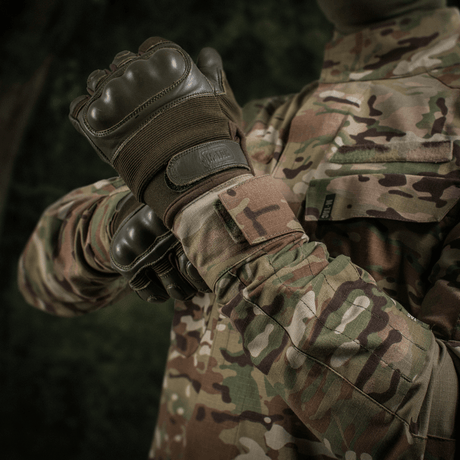 M-Tac Jakke Sturm NYCO Extreme i Multicam-mønster, militærjakke i slidstærkt nylon-bomuldsstof, vises i naturscene.