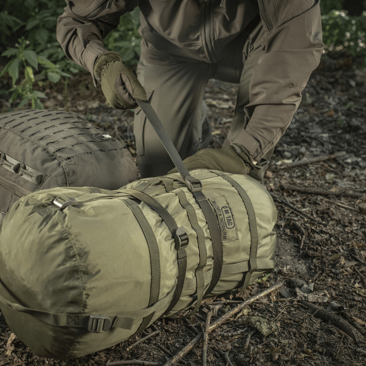M-Tac Kompressionsrem fastgjort til rygsæk under friluftstur for sikker opbevaring af ekstra udstyr, 100% nylon, 25 mm bred.