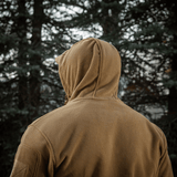 En person iført M-Tac Division Gen.II Windblock Fleecejakke foran skovbaggrund, ideel til beskyttelse mod køligt og koldt vejr.