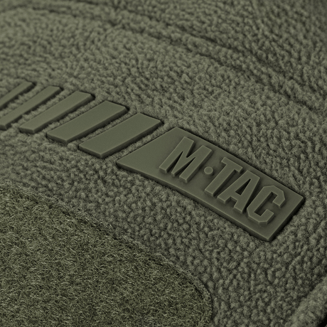 Detalje af M-Tac Division Gen.II Windblock Fleecejakke viser mærkelogo på olivengrøn polyester.