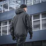 Mand bærer M-Tac Alpha Gen.III Pro Vinterjakke i bylandskab, fremhæver jakken som komfortabel og funktionel til kolde temperaturer.