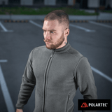 M-Tac Nord Polartec Fleecejakke i grå Polartec® 200 Series fleece, ideel til hverdag og sport, bæres af en mand på parkeringsplads.