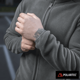 M-Tac Nord Polartec Fleecejakke anvist på en person rørende ved ærmet, fremstillet med premium Polartec® 200 Series fleece materiale.