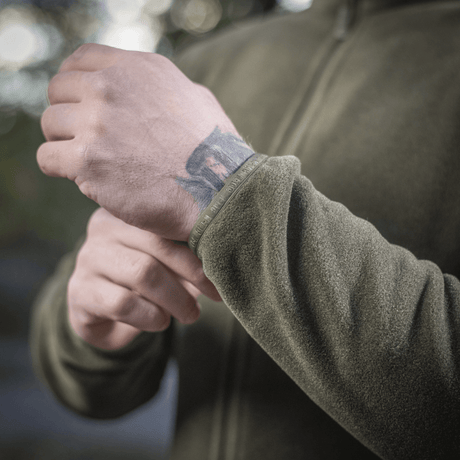 Detaljeret billede af M-Tac Nord Polartec Fleecejakke i brug udendørs, viser kvalitet og tekstur på det grønne fleece materiale.