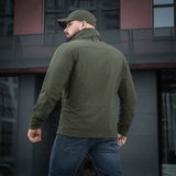 Mand iført M-Tac Flash Jakke foran moderne bygning. Let og alsidig jakke ideel til hverdag og aktiviteter. Ingen velcro på ærmerne.