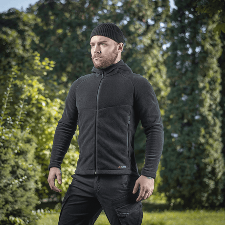 Mand iført M-Tac Sprint Fleece Sweatshirt Polartec i sort i frodigt skovmiljø, fremhæver stilfuld funktionalitet og komfort.