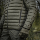 Mand i M-Tac Stalker Gen.III Jakke i skovmiljø, viser detaljeret syning og lynlås, perfekt til overgangssæsonen.