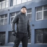 Mand iført M-Tac Stalker Gen.III Jakke i sort, stående foran moderne bygning, fremhæver stilfuldt og aggressivt design