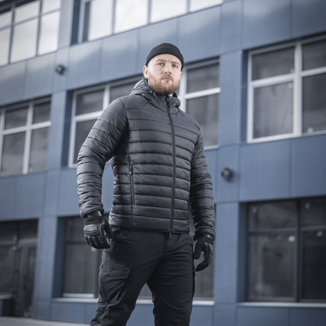 Mand iført M-Tac Stalker Gen.III Jakke i sort, stående foran moderne bygning, fremhæver stilfuldt og aggressivt design