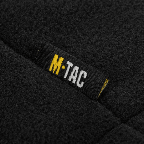 Etiket på M-Tac Combat Fleece Polartec Jakke i sort fleece materiale med M-Tac-logo. Perfekt til taktisk og casual brug. Høj kvalitet.