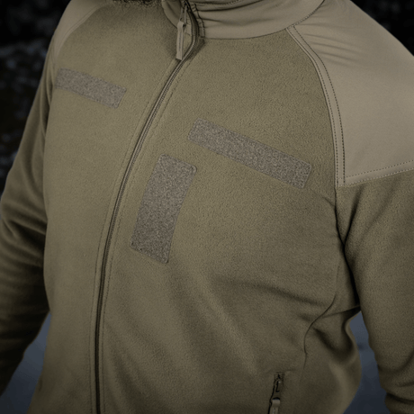 M-Tac Combat Fleece Polartec Jakke i olivengrøn med velcro-paneler og YKK lynlåse til taktisk og casual brug, vist tæt på.