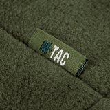 Detalje af M-Tac Combat Fleece Polartec Jakke med mærkelogo i olivengrøn farve, der viser høj kvalitet og avanceret design.
