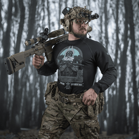 M-Tac Raglan Odin Mystery båret af mand i taktisk gear i skovmiljø.