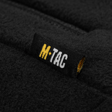 Nærbillede af M-Tac mærke på M-Tac Combat Fleece Jakke Polartec Dame i sort fleece materiale, designet til komfort og høj funktionalitet.
