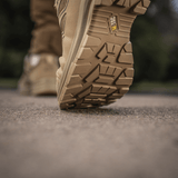 M-Tac Tactical Sneakers IVA i aktion på et udendørs underlag, viser den robuste sål ideel til trekking og outdoor-aktiviteter.