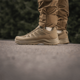 M-Tac Tactical Sneakers IVA på person iført brune bukser, lette og ventilerede sneakers, perfekte til sommeraktiviteter og outdoor-brug.