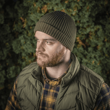 M-Tac Watch Cap 100% Akryl strikhue, perfekt til koldt vejr, på mand i skov, holder hovedet varmt og stilfuldt.