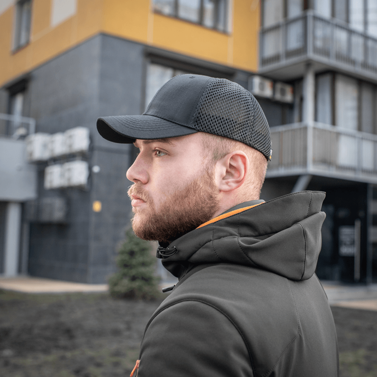 Mand iført en M-Tac Mesh Flex Ripstop Baseball Cap, perfekt til udendørs brug med let mesh for ventilation, set i et bymiljø.