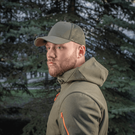 Mand iført M-Tac Mesh Flex Ripstop Baseball Cap i grøn, stående foran et træ i en udendørs setting.