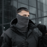 Mand iført M-Tac Polartec Lang Tubehalstørklæde i grå farve i koldt vejr, alsidig beskyttelse mod vind, perfekt til udendørsaktiviteter.