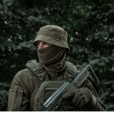 Person wearing tactical gear and hat in outdoor setting