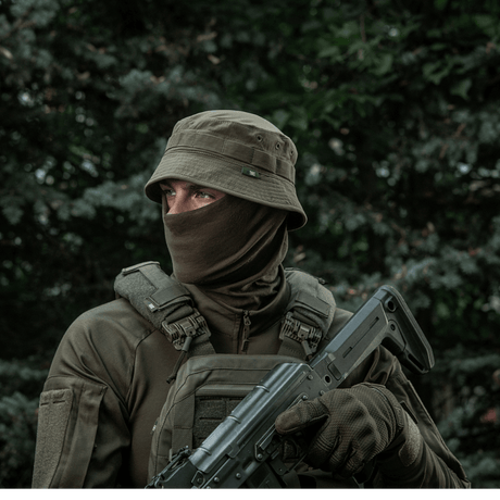 Person wearing tactical gear and hat in outdoor setting