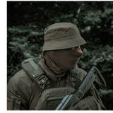 Militærperson iført M-Tac Panamahat Gen. II Summer Flex i skovmiljø, viser solbeskyttelse og komfort til varme sæsoner.