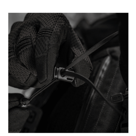 Næroptagelse af sort handske justerer en snøre på en M-Tac taske