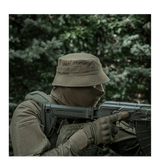 Person iført M-Tac Panamahat Gen. II Summer Flex i skovmiljø, klar til taktiske opgaver, fokus på komfort og kvalitet i varmt vejr.