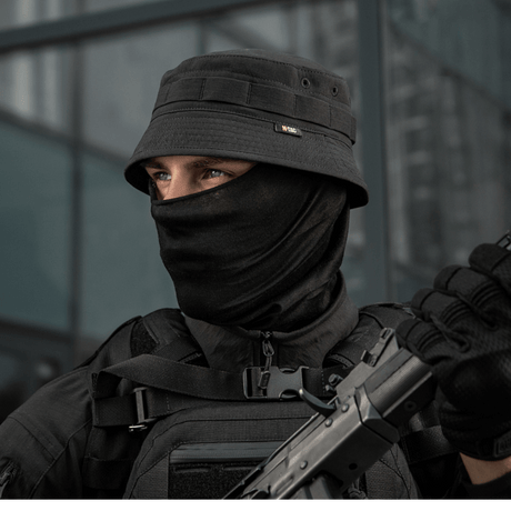 M-Tac Panamahat Gen. II Summer Flex i sort, bæres af en person i taktisk tøj, ideel til beskyttelse i solfyldte omgivelser.