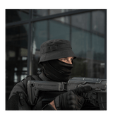 Person wearing tactical gear and holding a firearm, outdoors.