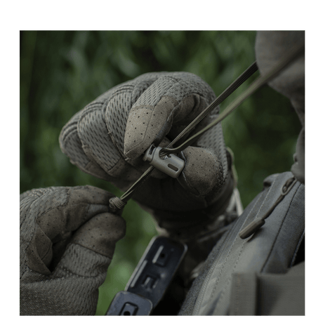 Person wearing tactical gloves adjusting equipment outdoors