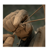 Taktisk hånd med handsker justerer udstyrssnøre i feltmiljø.