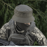 Person iført M-Tac Panamahat Gen. II Flex Rip-Stop i militært udstyr, viser slitstærk konstruktion og komfort i naturmiljø.