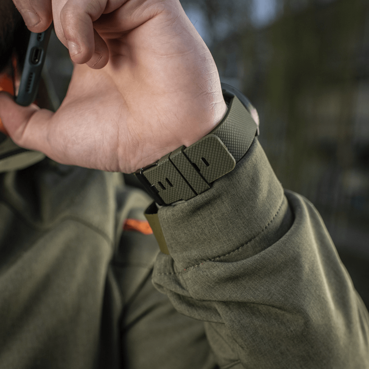 Person wearing M‑Tac Multifunktionelt Taktisk Ur med robust urkasse og rem, ideelt til friluftsliv og militærbrug.