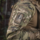 M-Tac Spartan Hjelm Patch på camouflagejakke symboliserer mod, styrke, og militær kraft, lavet af holdbart Cordura 500D materiale.