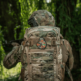 Soldat med camouflagerygsæk og M-Tac Patch Tiger Green Tape PVC i skoven, 3D morale patch af tiger med AR-15 og taktisk udstyr.