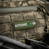 M-Tac Patch Autosave PVC 3D morale patch på en camouflage rygsæk, lavet af PVC, 8 x 2.5 cm, med fuld farve og velcro bagside.