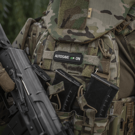 M-Tac Patch Autosave PVC på en camouflagejakke med magasinlommer, der viser detaljeret 3D-design og farveklarhed, ideel til taktisk brug.