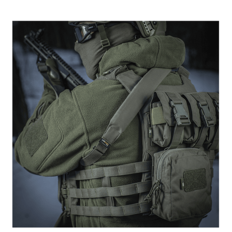 M-Tac Universal Våbenrem i brug udendørs, vist på en soldat med taktisk udstyr for maksimal komfort og let håndtering af gevær.