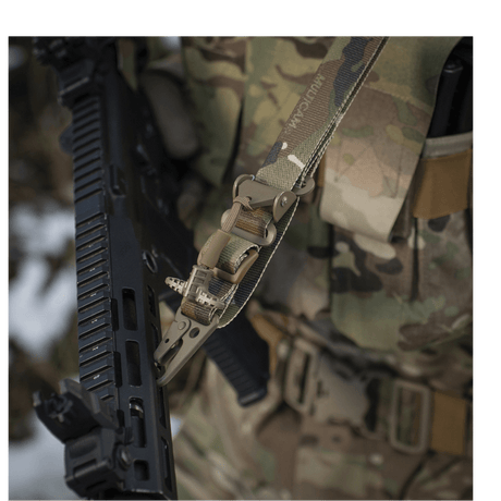 Detaljeret billede af M-Tac Universal Våbenrem fastgjort til kamuflageudstyr, der viser det multifunktionelle design og karabinhagen.
