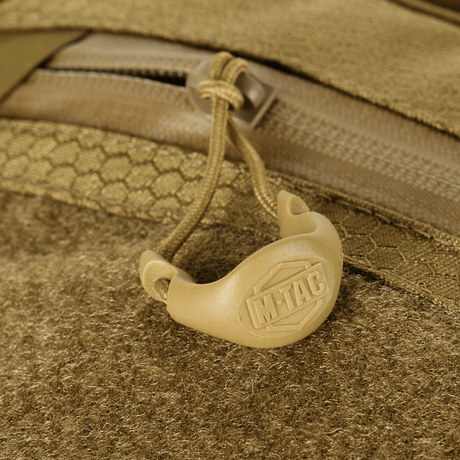 Detalje af M-Tac Sling Pistol Taske Elite Hex med Velcro, viser lynlås og håndtag med logo, lavet af slidstærk Cordura-materiale.